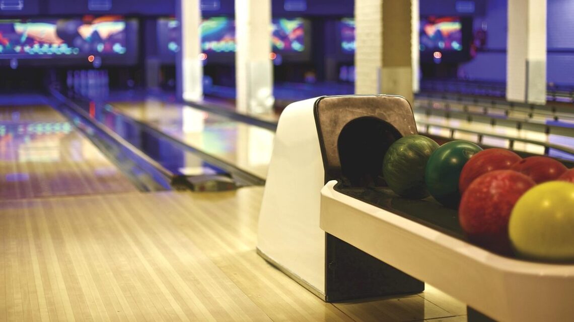 Allée de bowling avec pistes, boules colorées et sièges