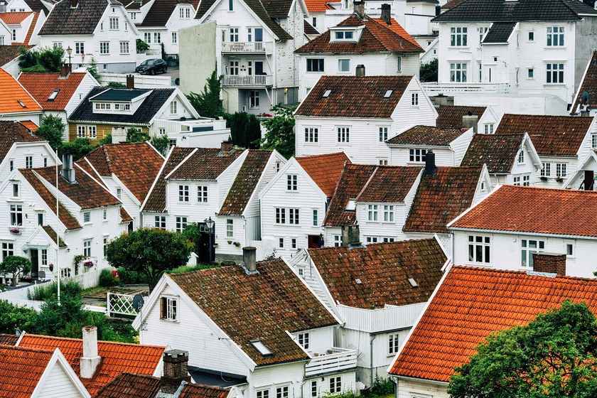 Vue aérienne de maisons blanches avec toits rouges et verts, entourées de végétation