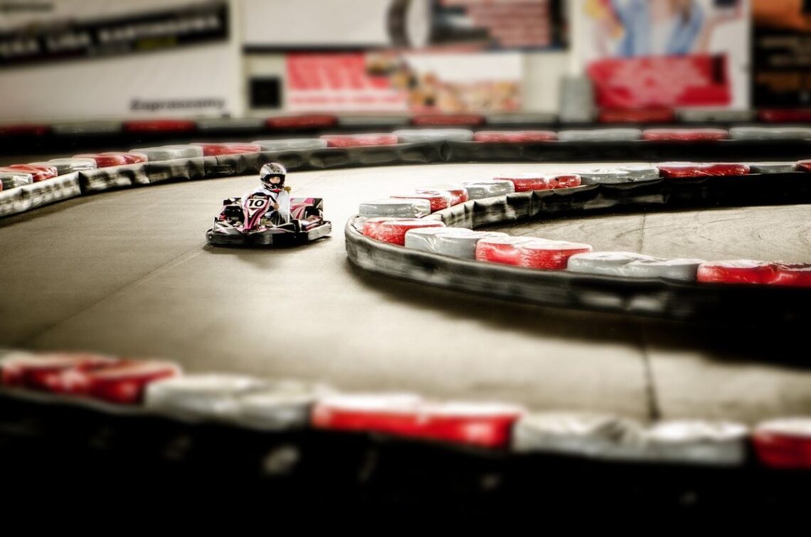 Un kart miniature tourne sur un circuit indoor bordé de protections